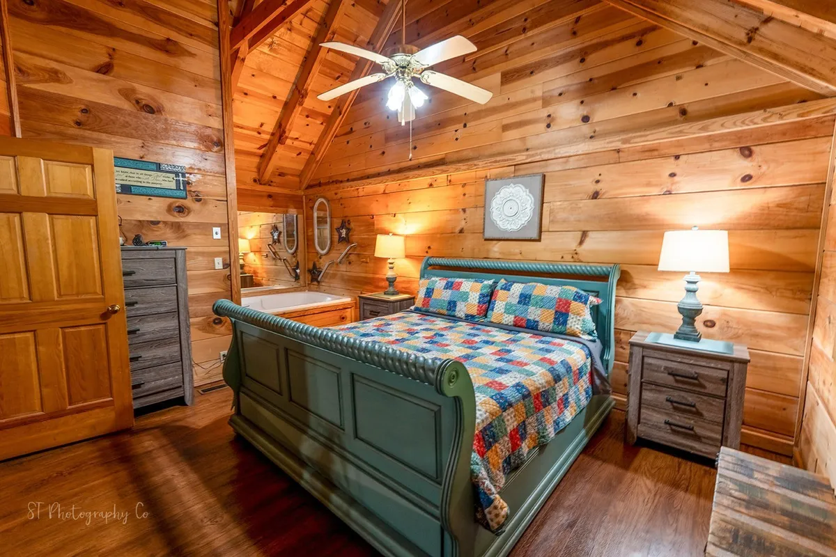 A cozy bedroom scene with a wooden bed flanked by bedside lamps, all set against rustic wooden walls. The inviting setup suggests a peaceful spot to rest, read, or converse after a day of adventure.