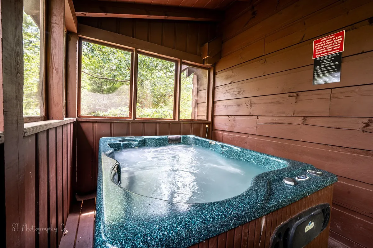This image features a hot tub set against large windows, surrounded by warm wood paneling. The view through the windows connects guests to the outdoors, hinting at the natural setting that surrounds the cabin. The tranquil mood and nature views evoke a sense of relaxation after a day spent exploring with your dog.