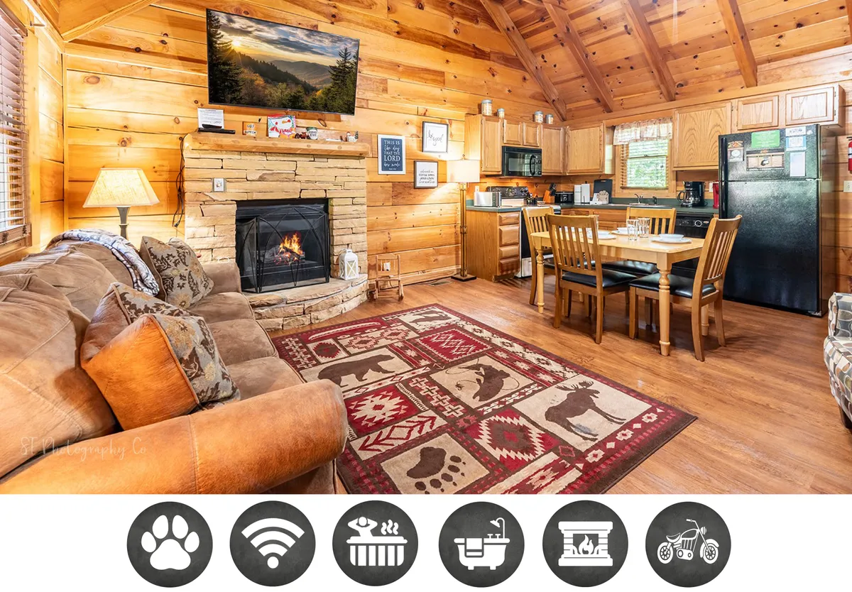 The image showcases a cozy cabin interior with a glowing fireplace as the centerpiece, a plush rug, a welcoming dining table set for gathering, and a fully equipped kitchen area. The inviting arrangement sets the stage for warmth, togetherness, and relaxation, perfect for couples or small families.