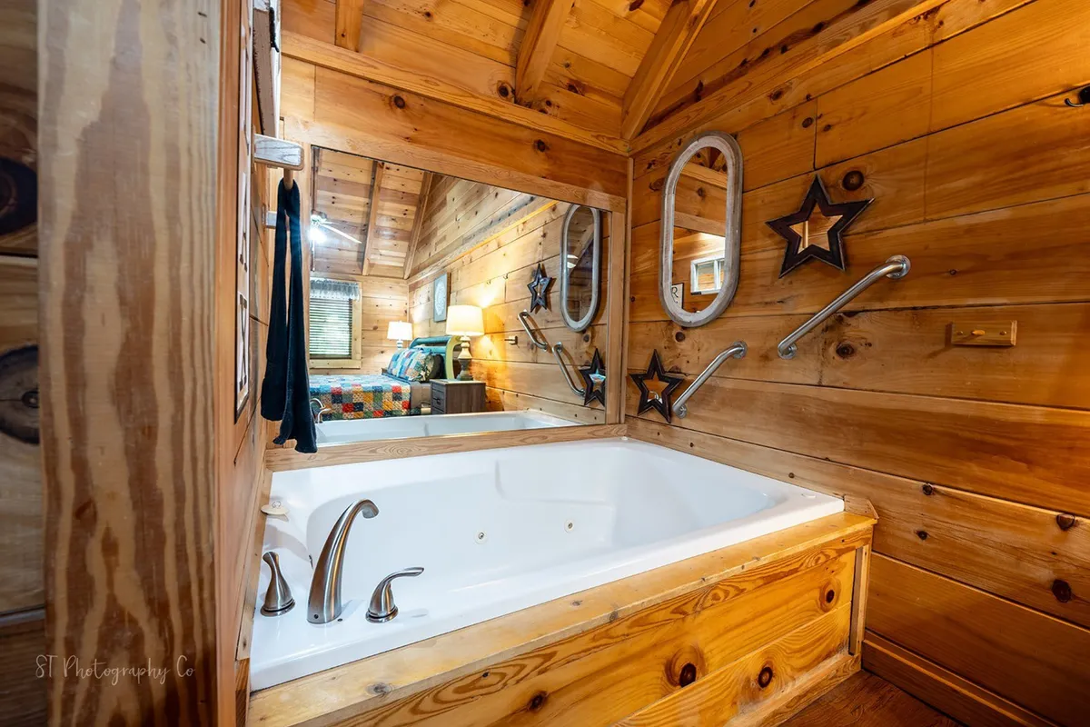 This image presents a tranquil bathroom scene, featuring a bathtub surrounded by warm wooden walls and adorned with decorative star accents. The large mirror and soft lighting evoke a peaceful, retreat-like atmosphere perfect for unwinding.